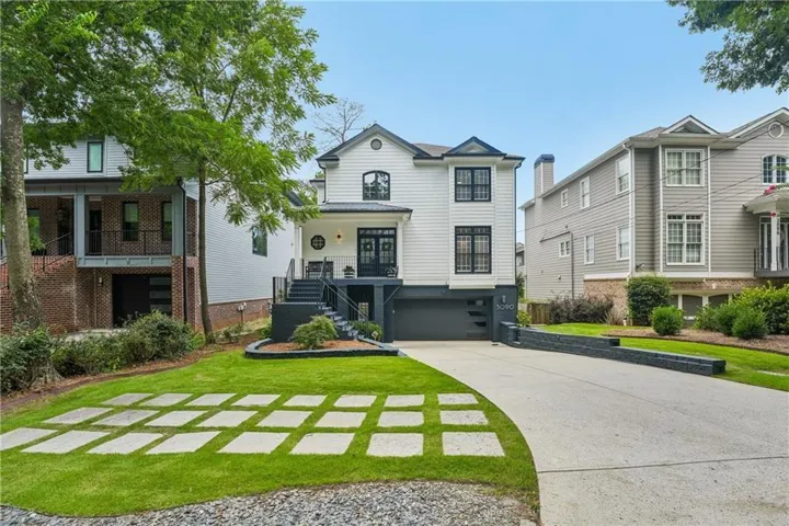 Modern dwelling with white siding, black trim accents, a front-facing garage, and a concrete driveway