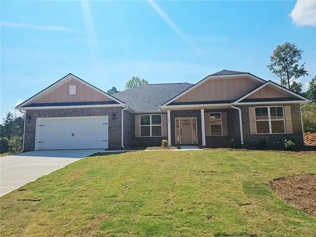 Brick exterior with tan siding gables, attached two-car garage, and a concrete driveway