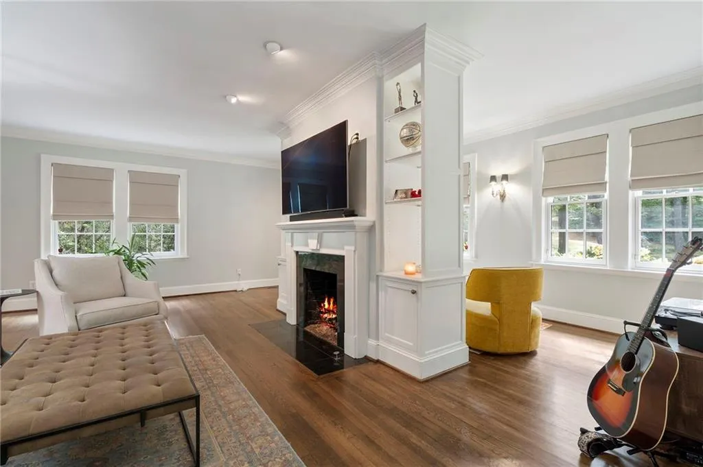 Living area with crown molding, dark wood-style floors, and a high end fireplace