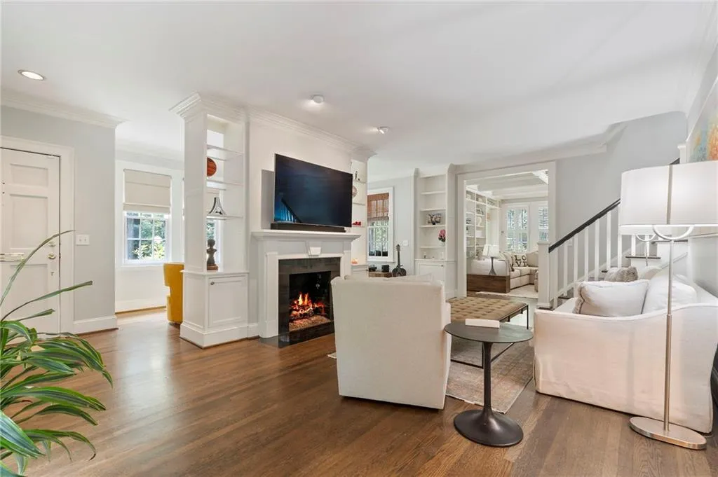 Living room with plenty of natural light, built in features, wood finished floors, and crown molding