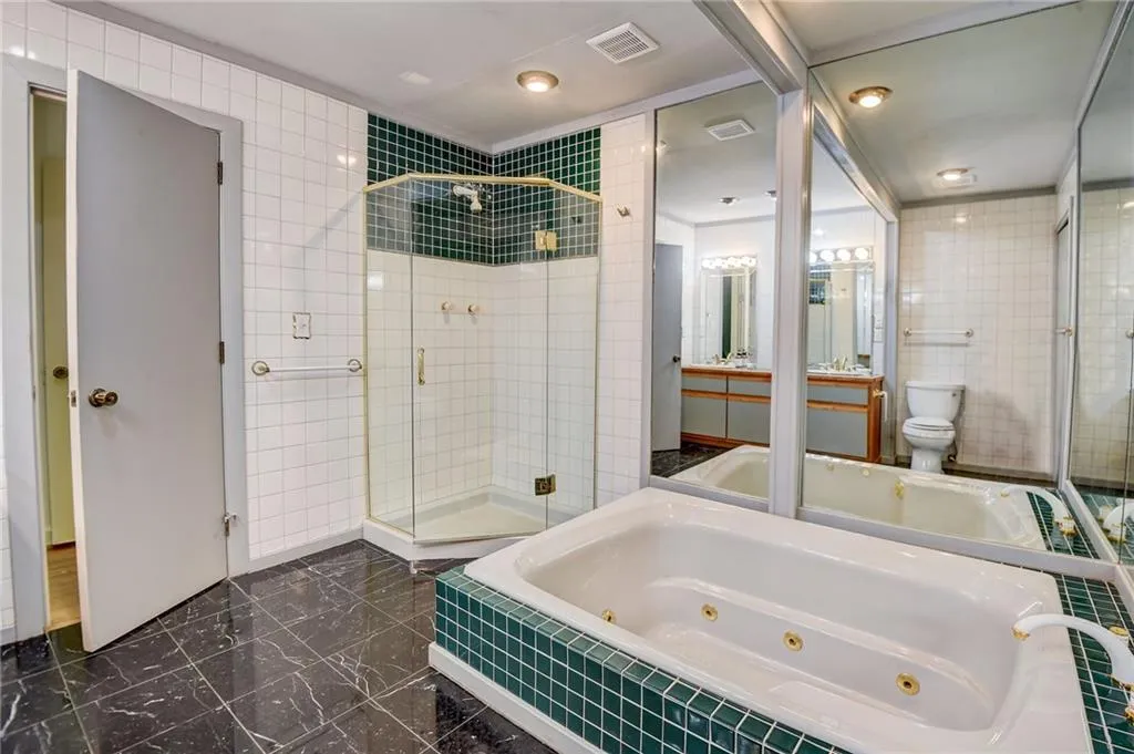 Bathroom with a shower with shower door, toilet, tile floors, and tile walls