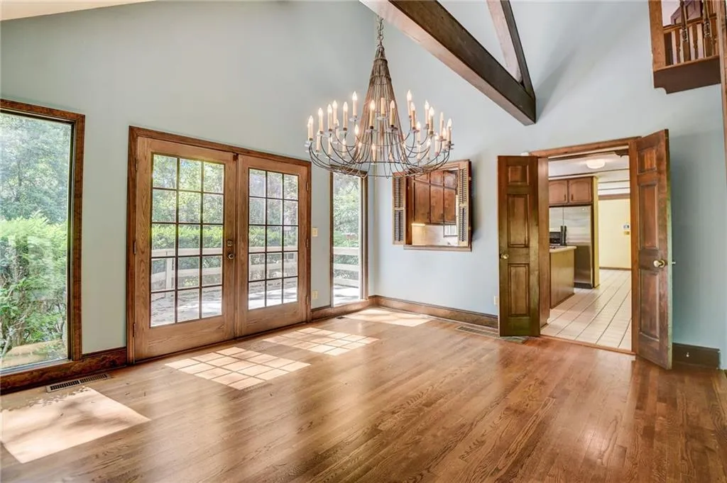 Dining room  high vaulted ceiling, beamed ceiling, french doors, light hardwood / wood-style flooring, and a chandelier