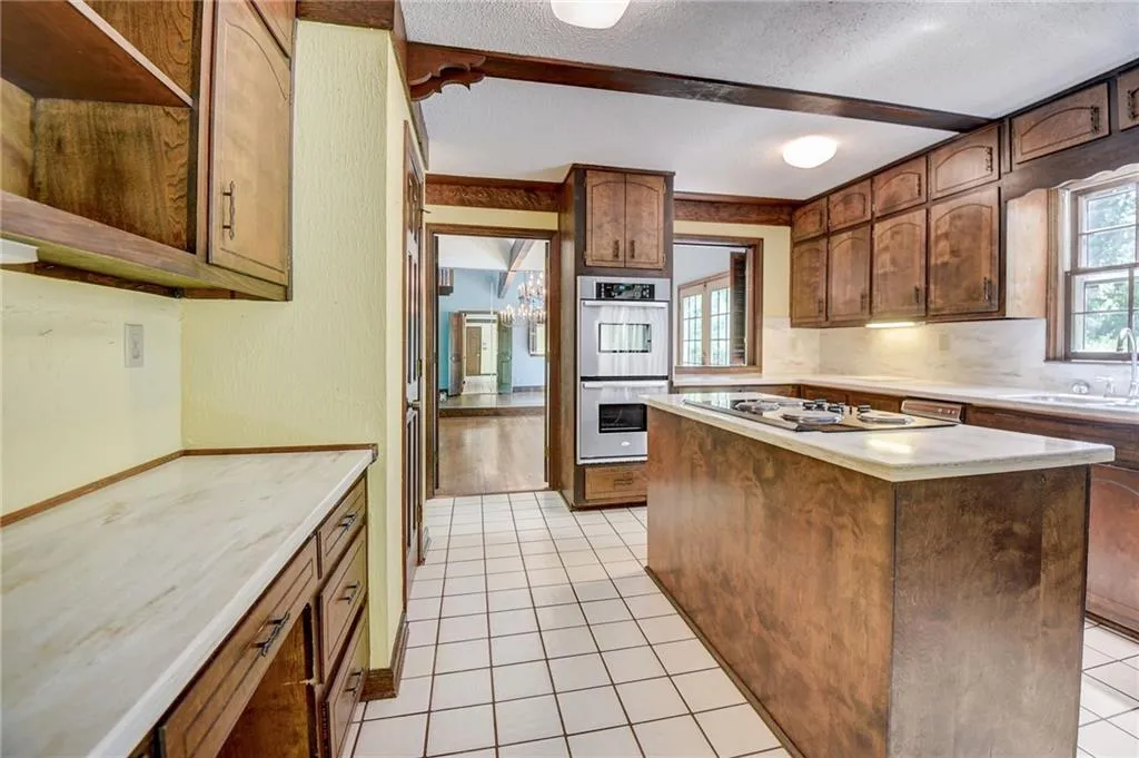 Kitchen featuring a center island, gas cooktop, sink, light tile floors, and stainless steel double oven