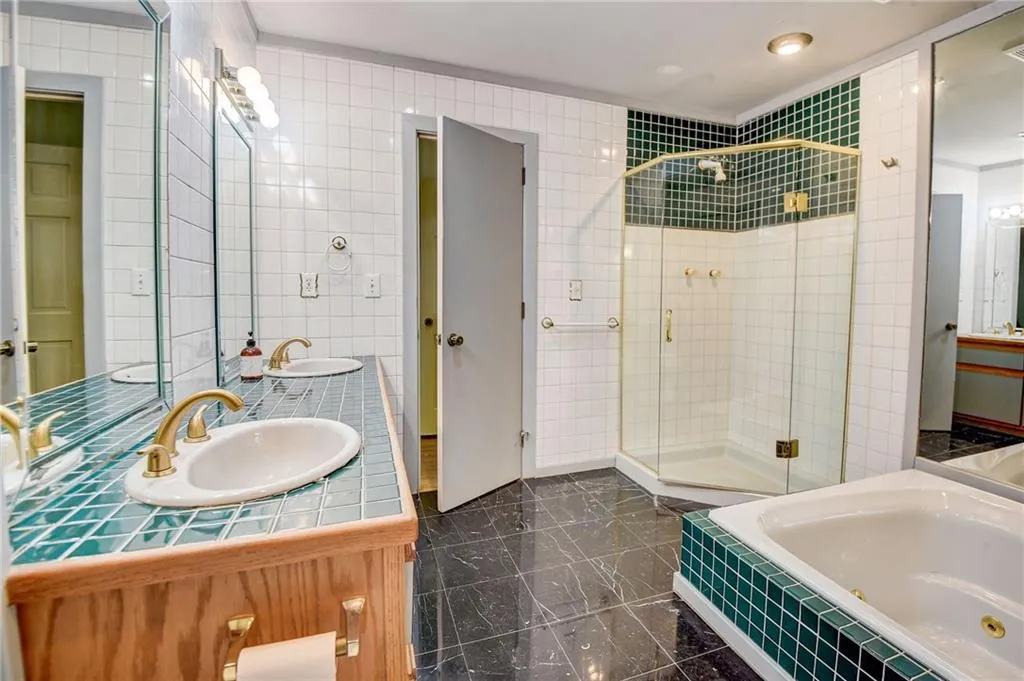 Bathroom with tile walls, tile floors, dual vanity, and shower with separate bathtub