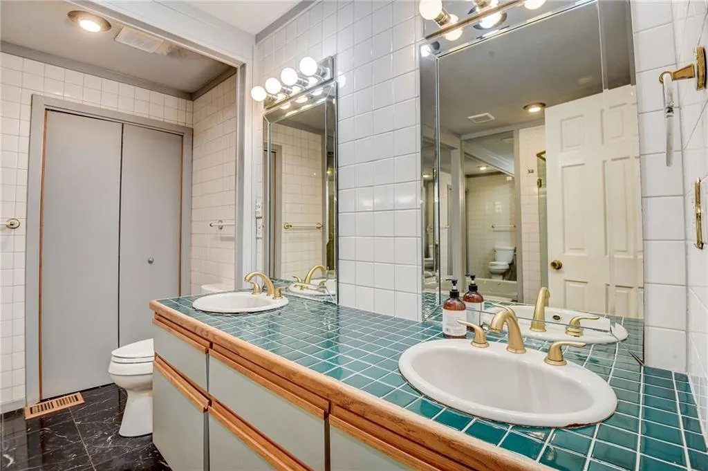 Bathroom with toilet, tile flooring, tile walls, and double sink vanity