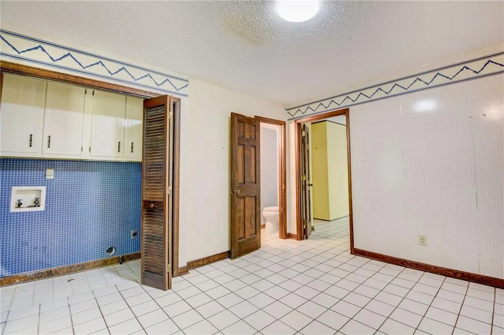 Flex room with 1/2 bath light tile flooring and a textured ceiling,