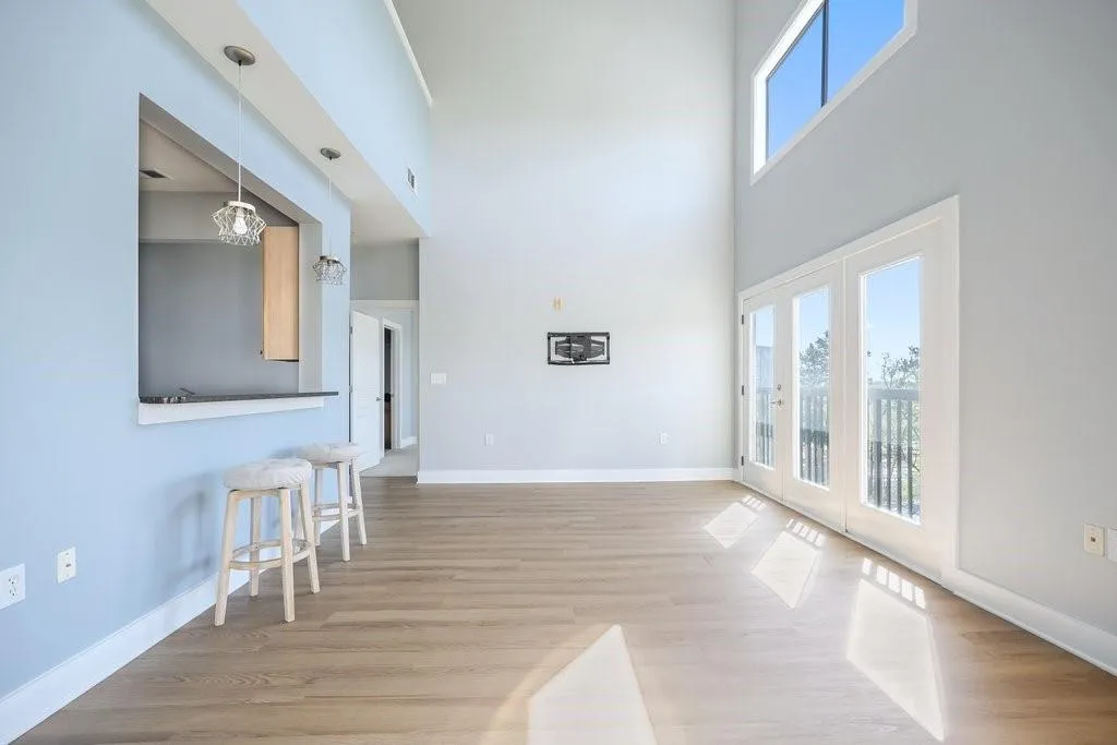 Living room with a high ceiling, a notable chandelier, french doors, and light wood-type flooring Living room with a high ceiling, a notable chandelier, french doors, and light wood-type flooring
