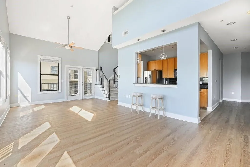 Unfurnished living room featuring a high ceiling, ceiling fan, and light wood-type flooring Unfurnished living room featuring a high ceiling, ceiling fan, and light wood-type flooring