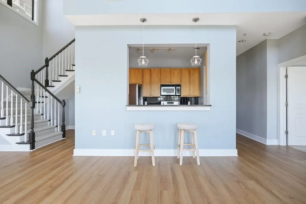 Kitchen with backsplash, light hardwood / wood-style floors, decorative light fixtures, and refrigerator Kitchen with backsplash, light hardwood / wood-style floors, decorative light fixtures, and refrigerator