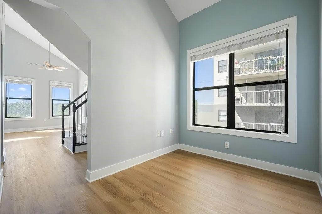 Empty room featuring lofted ceiling, ceiling fan, and light wood-type flooring Empty room featuring lofted ceiling, ceiling fan, and light wood-type flooring