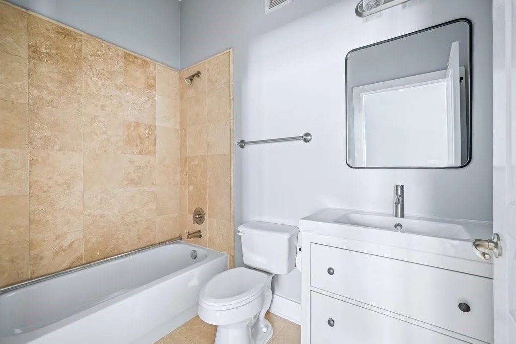 Full bathroom with tile floors, toilet, vanity, and tiled shower / bath Full bathroom with tile floors, toilet, vanity, and tiled shower / bath