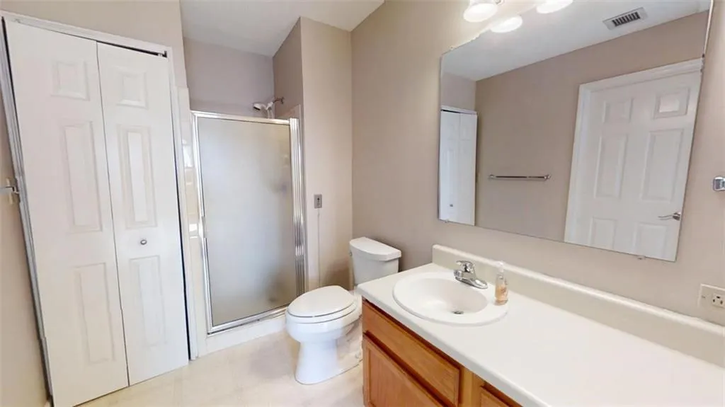 Full bathroom featuring a closet, visible vents, a shower stall, and toilet