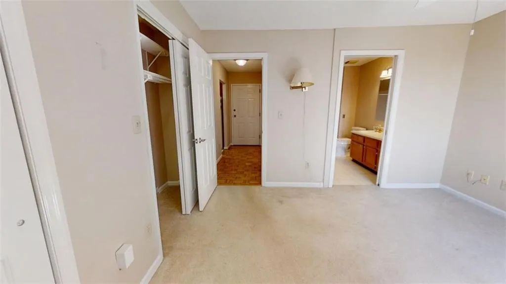 Unfurnished bedroom featuring light colored carpet, baseboards, and ensuite bathroom