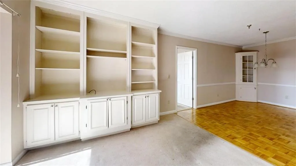 Spare room with an inviting chandelier, baseboards, and ornamental molding