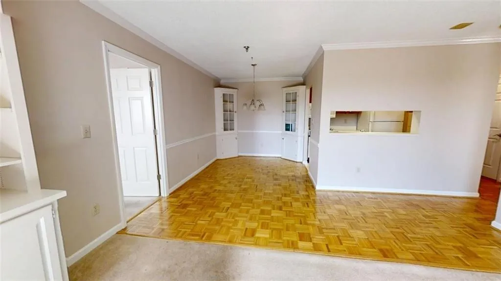 Unfurnished dining area with baseboards, crown molding, and an inviting chandelier