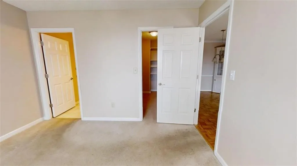Unfurnished bedroom with light carpet, a spacious closet, baseboards, and a closet