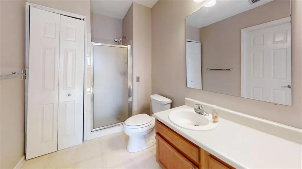 Full bath featuring toilet, visible vents, vanity, a closet, and a stall shower