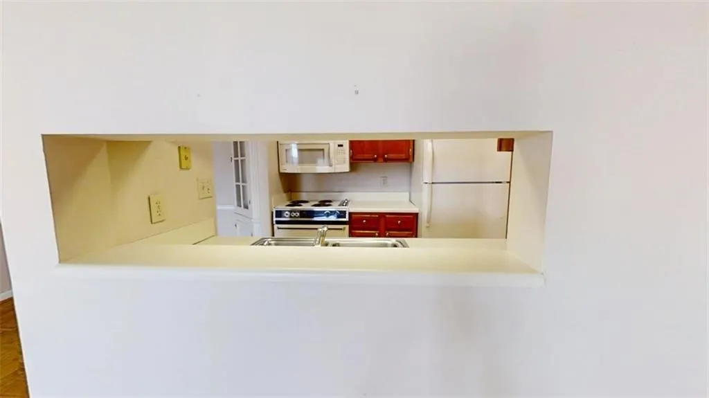 Kitchen with light countertops, white appliances, and a sink