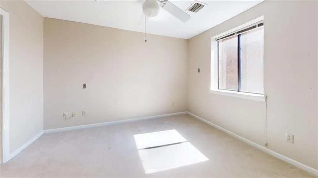 Unfurnished room with a ceiling fan, light colored carpet, visible vents, and baseboards