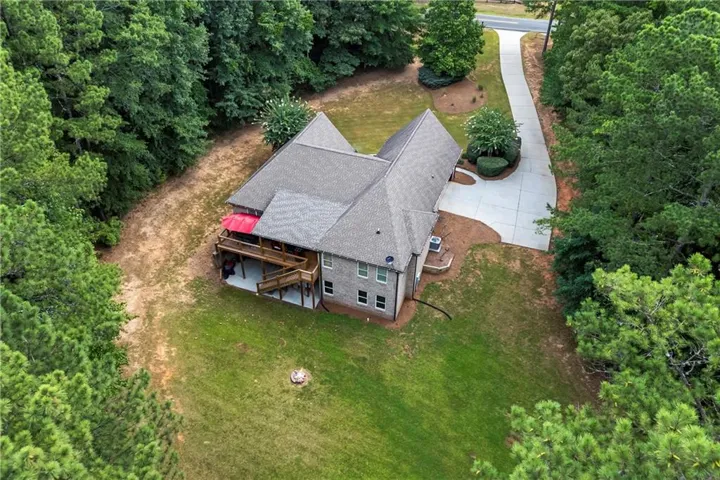 Property featuring a multi-level deck, expansive green lawn, mature trees, and a concrete driveway
