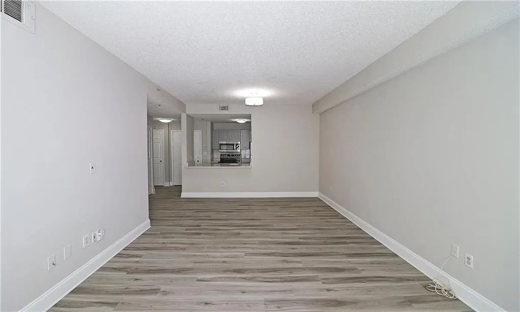 Spare room featuring baseboards, wood finished floors, visible vents, and a textured ceiling