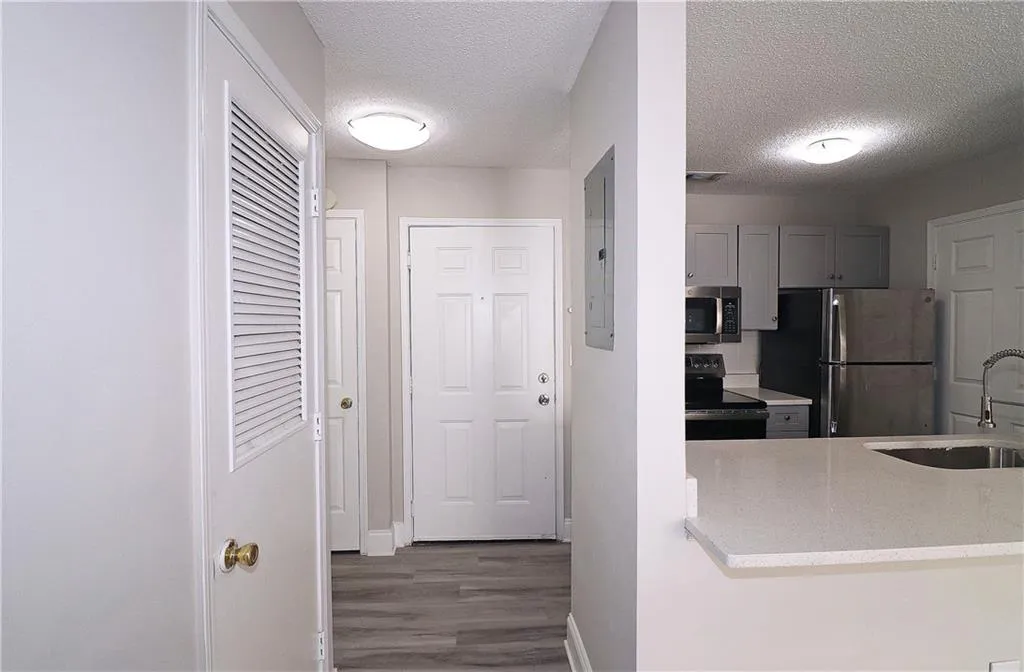 Kitchen featuring gray cabinets, a sink, electric panel, a textured ceiling, and appliances with stainless steel finishes