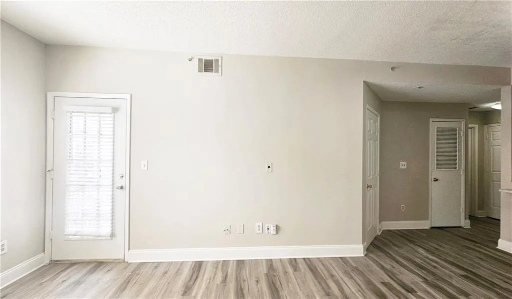 Unfurnished room with wood finished floors, a healthy amount of sunlight, visible vents, and baseboards