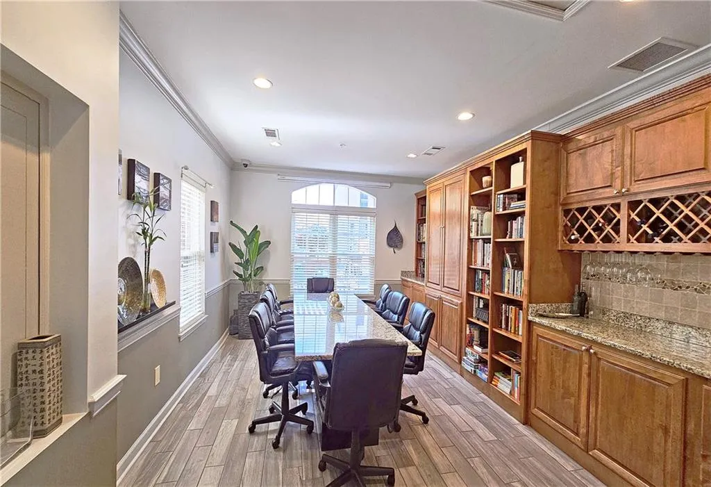 Office area with crown molding, light wood-style floors, and visible vents
