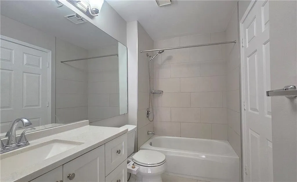 Bathroom featuring vanity, toilet, tub / shower combination, and visible vents