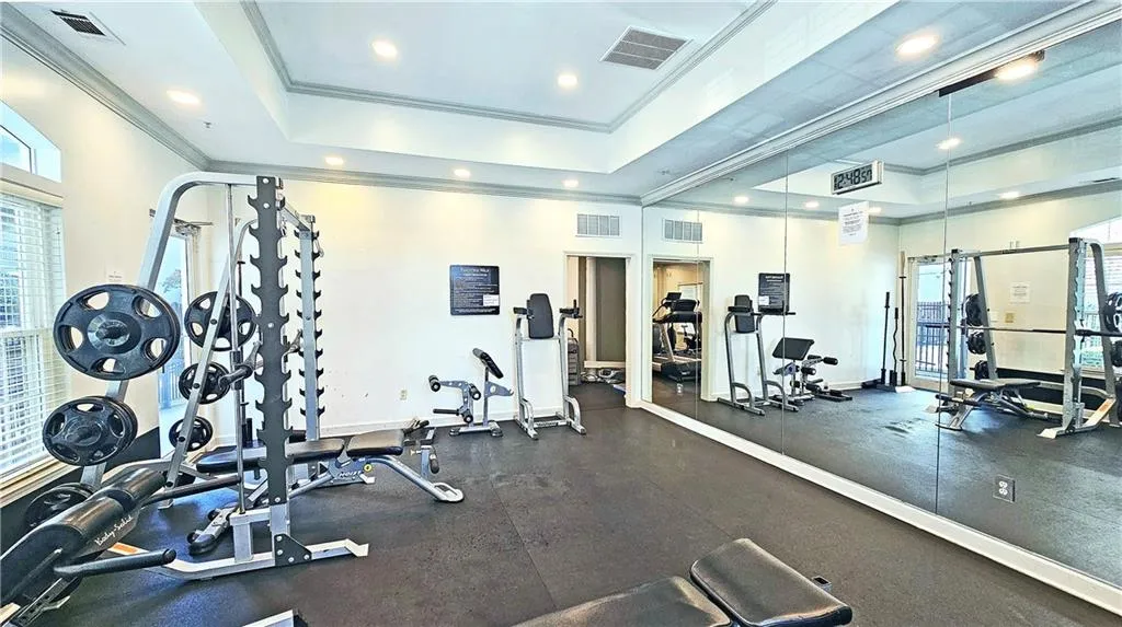 Workout area featuring visible vents, a raised ceiling, and ornamental molding