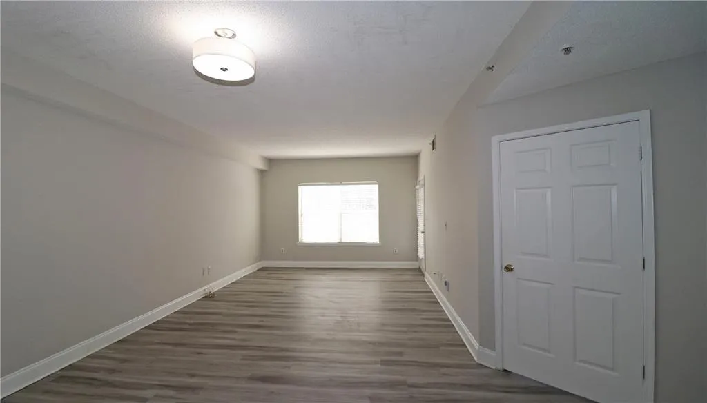 Empty room featuring baseboards, a textured ceiling, and wood finished floors