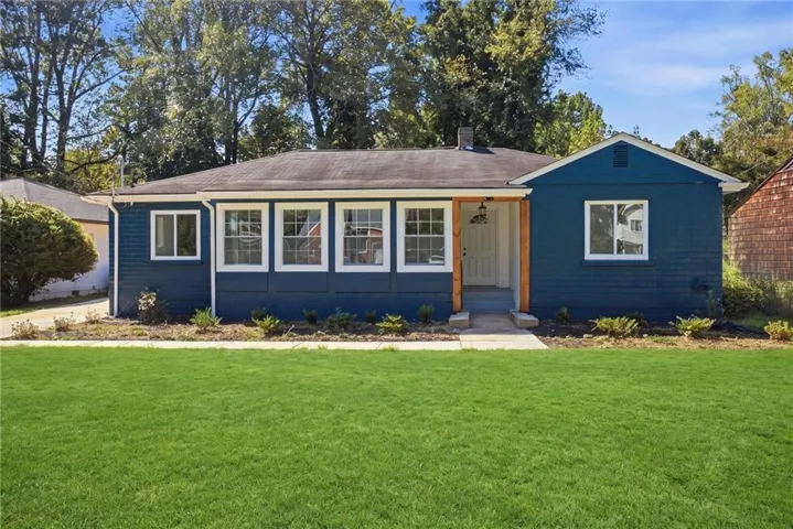 Freshly painted exterior with a deep blue finish, multiple white-framed windows, and a covered entryway with natural wood pillars