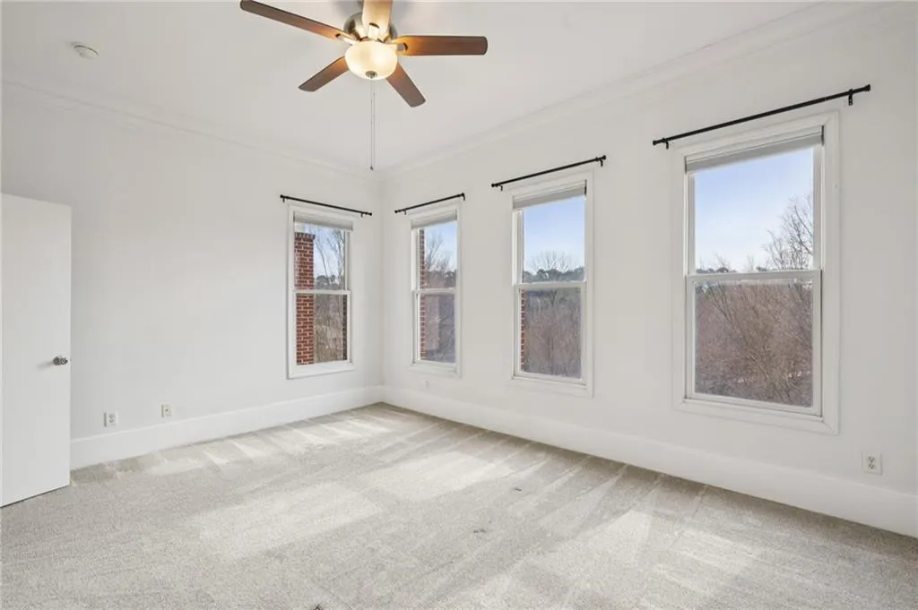 Primary bedroom featuring ornamental molding, light carpet, and a ceiling fan.