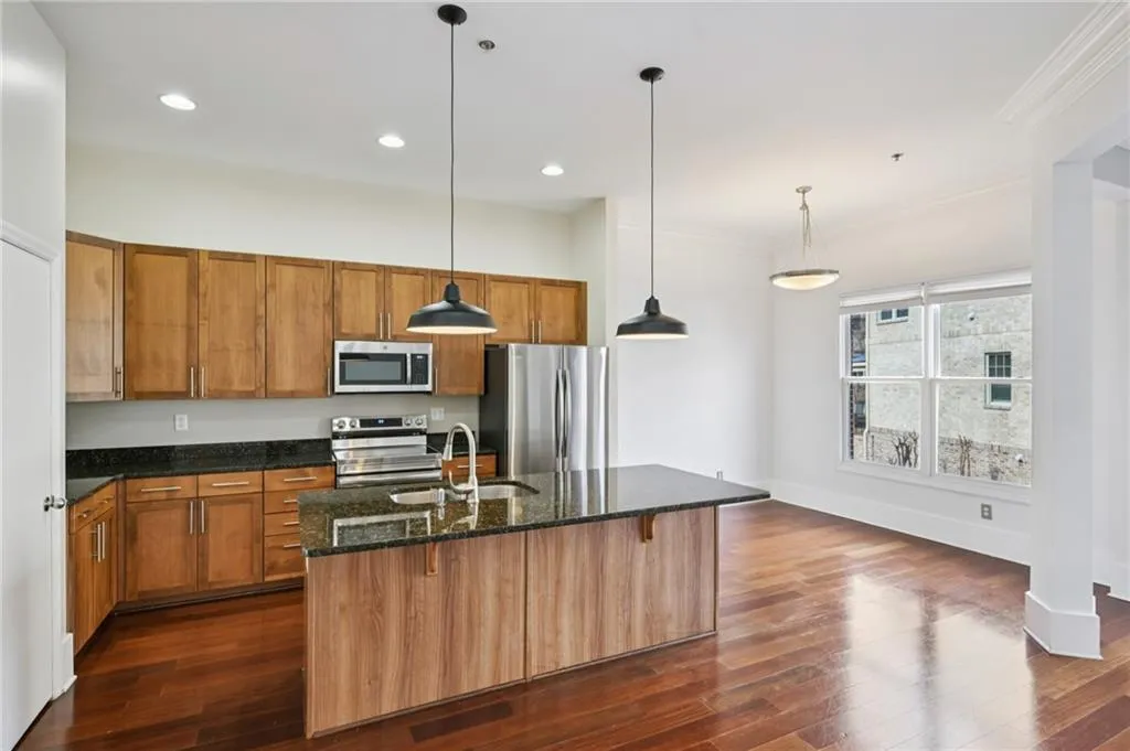 Kitchen with wood finish cabinets (fronts just replaced), granite countertops, hanging light fixtures, stainless steel appliances, and dark wood finished floors. Eat-in at island or set up a table and chairs in the space right of frame. Pantry on left.