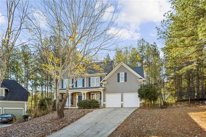 Two-story residence featuring a covered front porch, a two-car garage, and shuttered windows