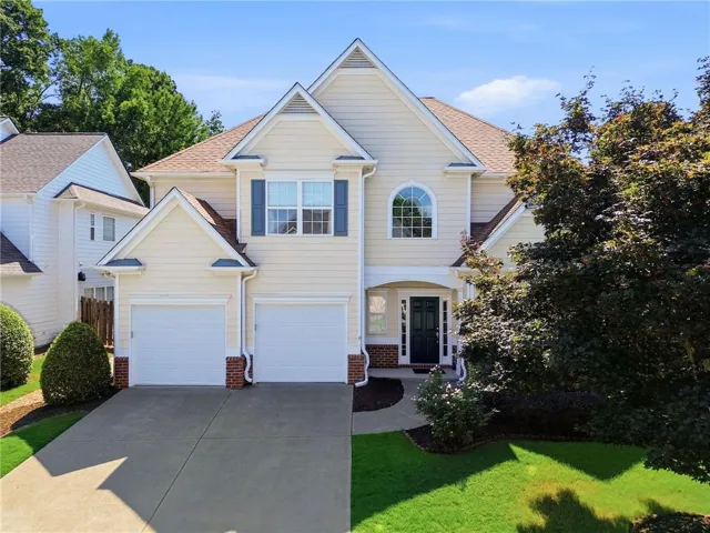 Two-story residence featuring light-colored siding, a dark entry door, multiple gables, and a two-car garage