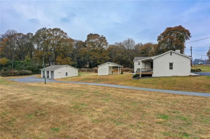White brick residence with a covered side porch and a detached two-car garage