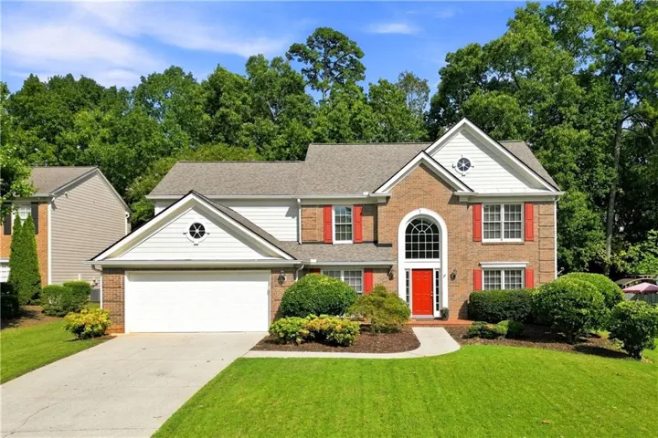 Brick and siding exterior with a gabled roof, arched entry, red front door, and a two-car garage