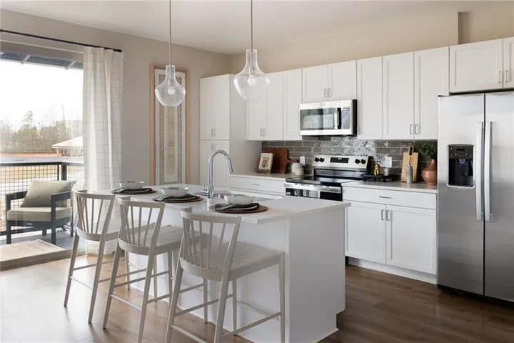 Kitchen featuring stainless steel appliances, white cabinets, a breakfast bar, backsplash, and pendant lighting