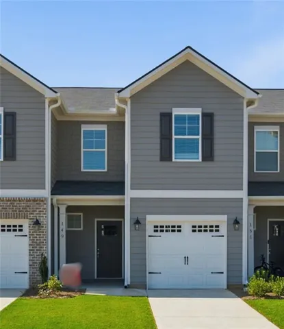 Two-story exterior with gray siding, white trim accents, a single-car garage, and a covered entry