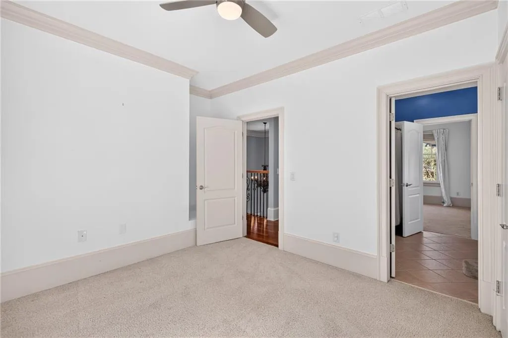 Room featuring carpeted flooring, neutral wall paint, crown molding, and an integrated ceiling fan with a light fixture