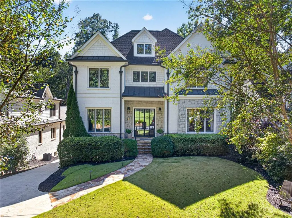 Two-story exterior featuring painted brick, natural stone masonry, shake siding, dark metal roofing accents, and a flagstone walkway