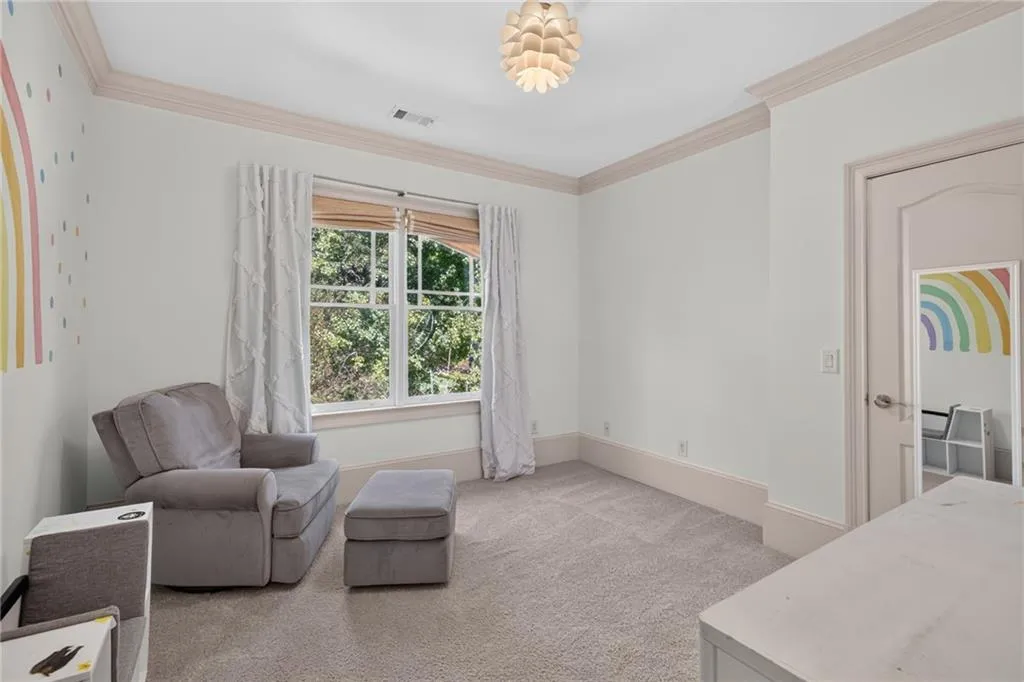 Neutral-toned room featuring crown molding, carpeting, multi-pane windows, and a decorative pendant light fixture
