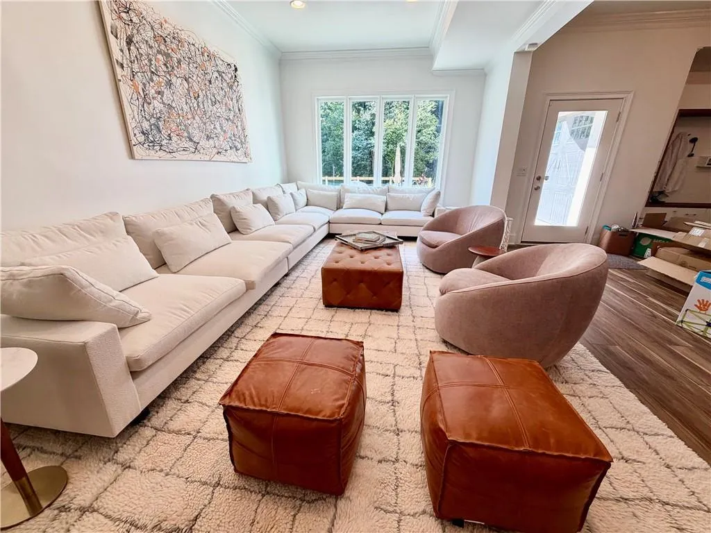 Living area featuring wood-finish flooring, recessed lighting, crown molding, and large windows with outdoor scenery