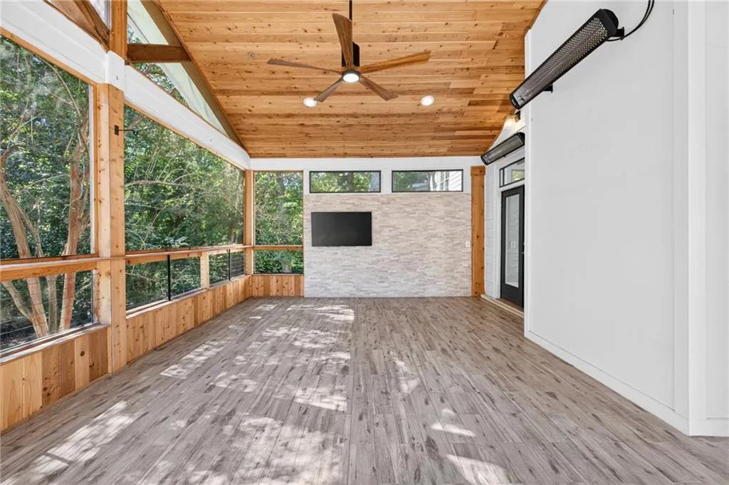 Screened porch featuring wood-plank vaulted ceiling, wood-finish flooring, stacked stone accent wall, and wall-mounted infrared heating units