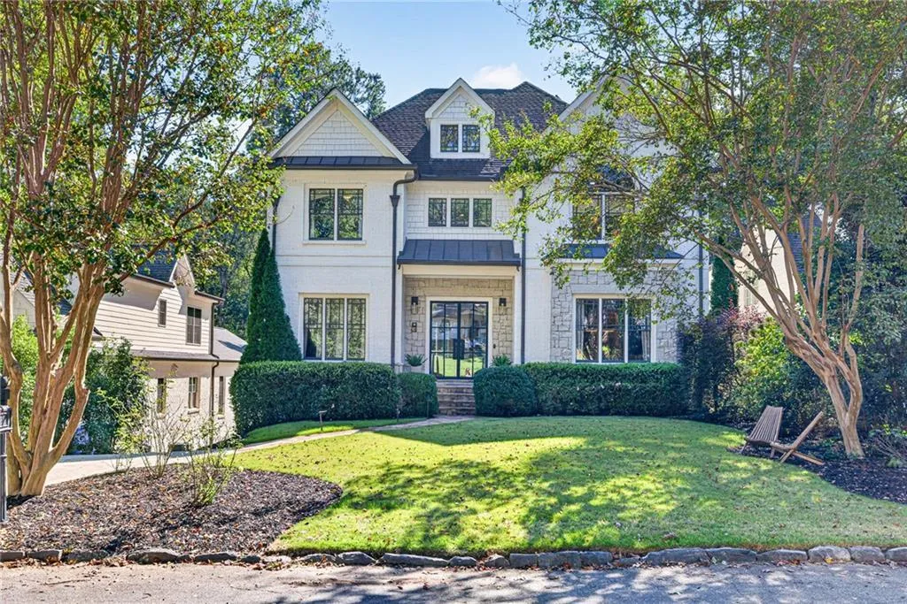 Multi-story residence featuring white painted brick and stone exterior, steep gable rooflines, shingle siding accents, and a covered entry with metal roofing