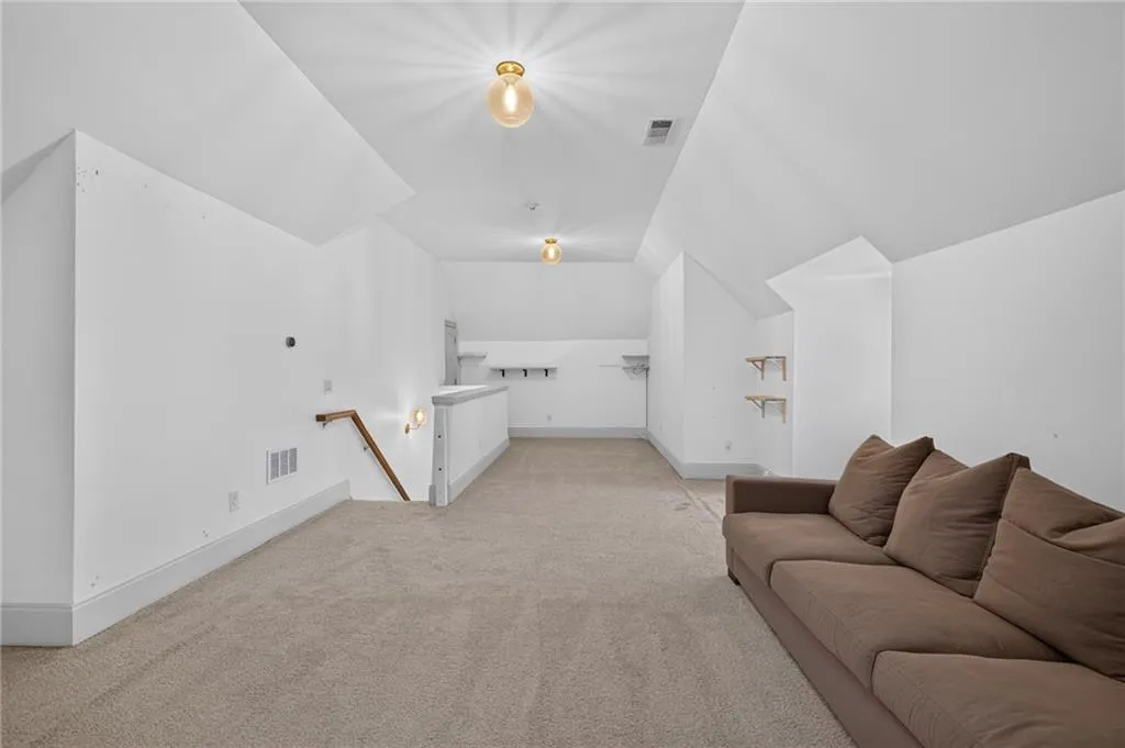Vaulted ceilings, neutral carpeting, flush-mount globe light fixtures, wall-mounted shelving units, and a wooden handrail