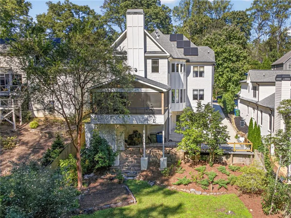Multi-level exterior featuring white siding, a chimney with vertical detailing, solar panels, a screened-in porch, and stone hardscaping
