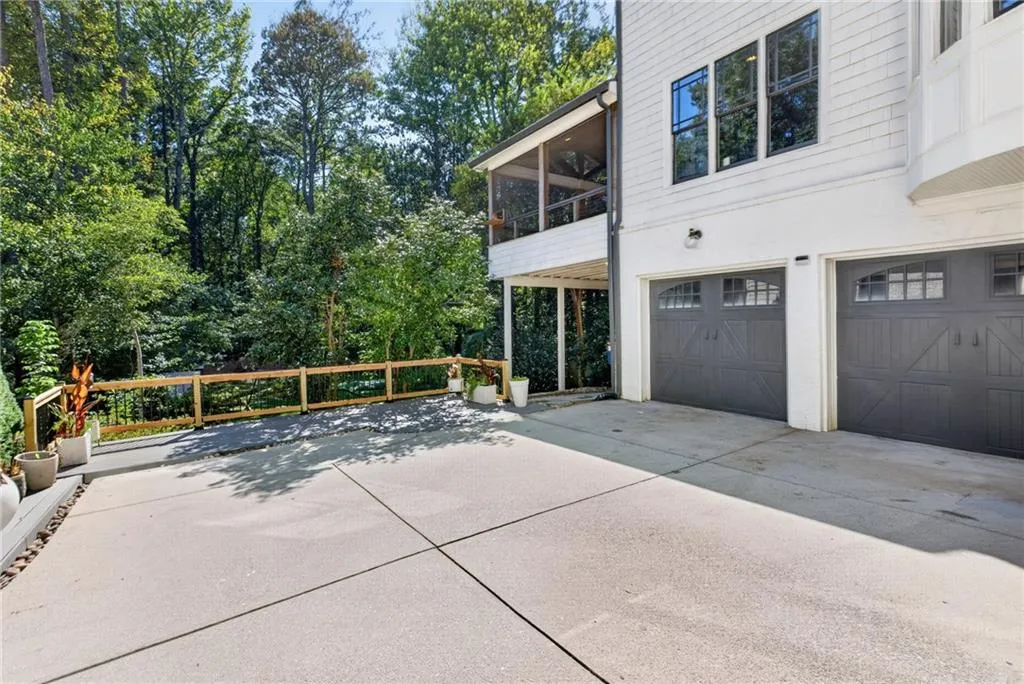 Two-car garage with dark-toned carriage-style doors, elevated screened porch, concrete driveway, and white siding exterior
