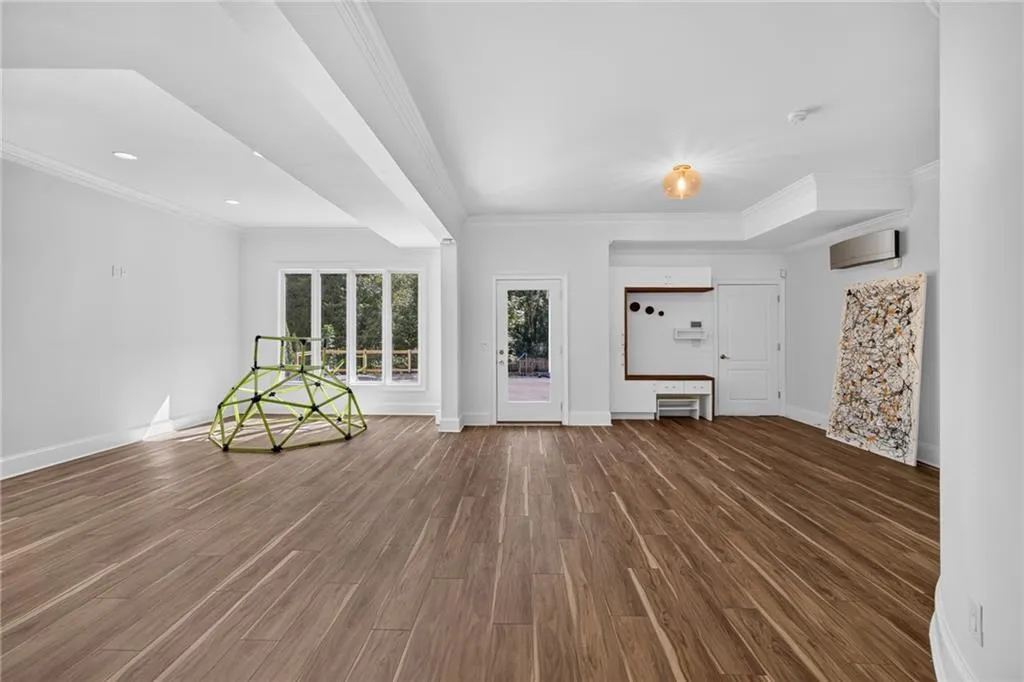 Open-concept space featuring wood-finish flooring, recessed lighting, crown molding, multi-pane windows, and a built-in bench with wall-mounted shelving